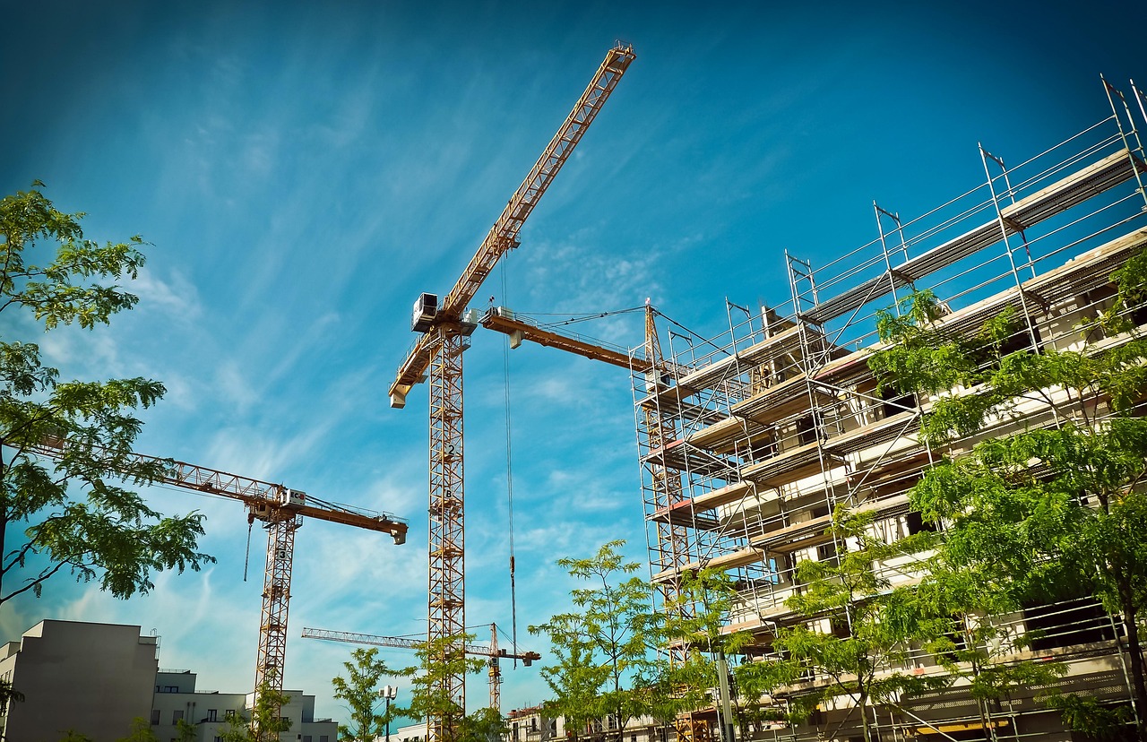 Ramky Infrastructure RVNL contract: multi-storey residential building under construction with scaffolding and tower cranes