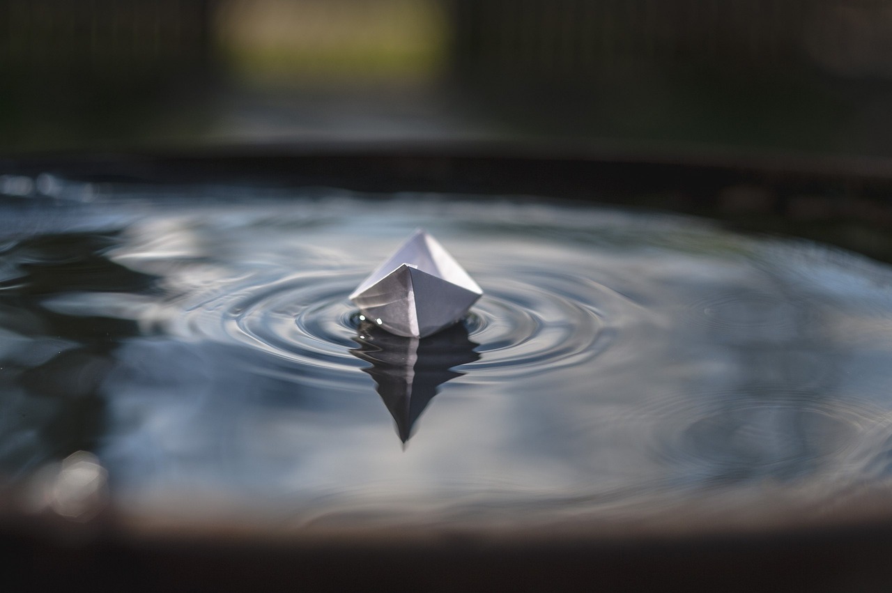 Unrealised gain in results concept: a small white paper boat floating on rippling water, standing for a profit that exists only on paper