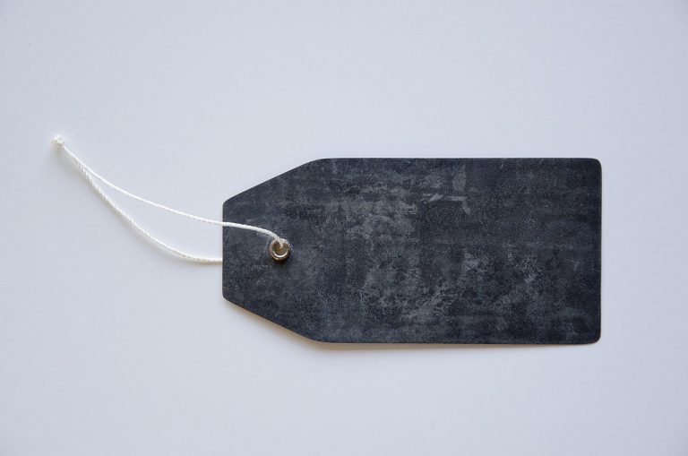 Fixed price issue concept: a blank dark price tag on a white string, standing for one IPO price set before the offer opens