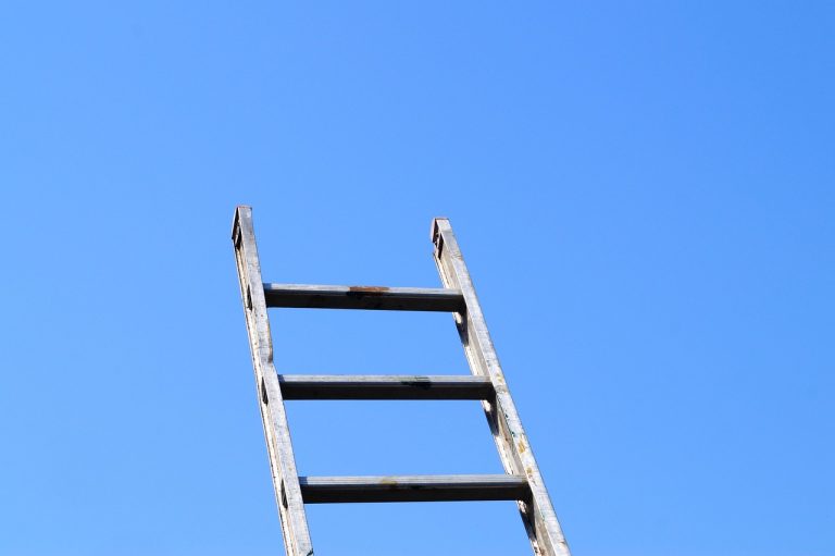 Bear call ladder concept: a metal ladder with three rungs rising into a clear blue sky, like the three call legs of the trade