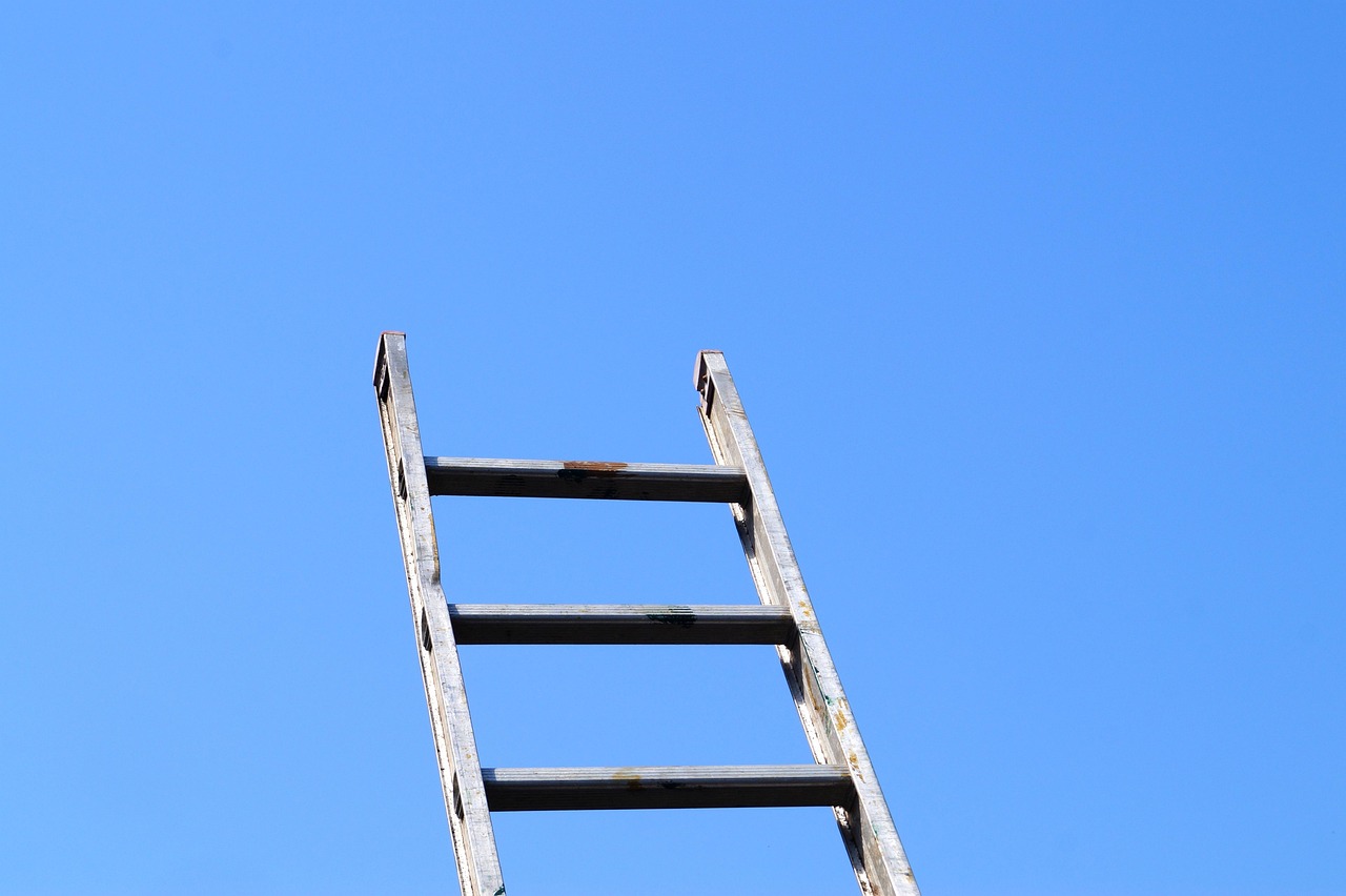 Bear call ladder concept: a metal ladder with three rungs rising into a clear blue sky, like the three call legs of the trade