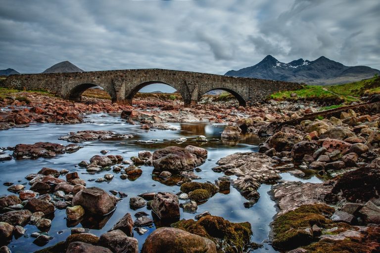 Debt service coverage ratio: an old stone arch bridge carrying its load across a rocky river, like earnings carrying debt repayments