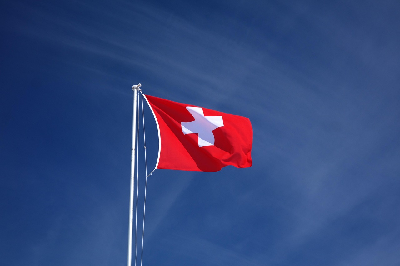 360 ONE UBS stake: Swiss flag flying on a flagpole against a blue sky
