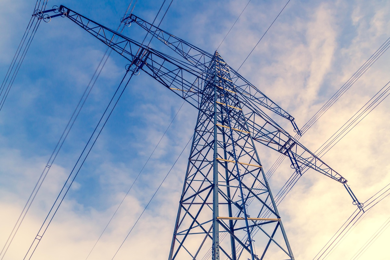 InvIT investing in India: steel power transmission tower and high-voltage lines against a blue sky
