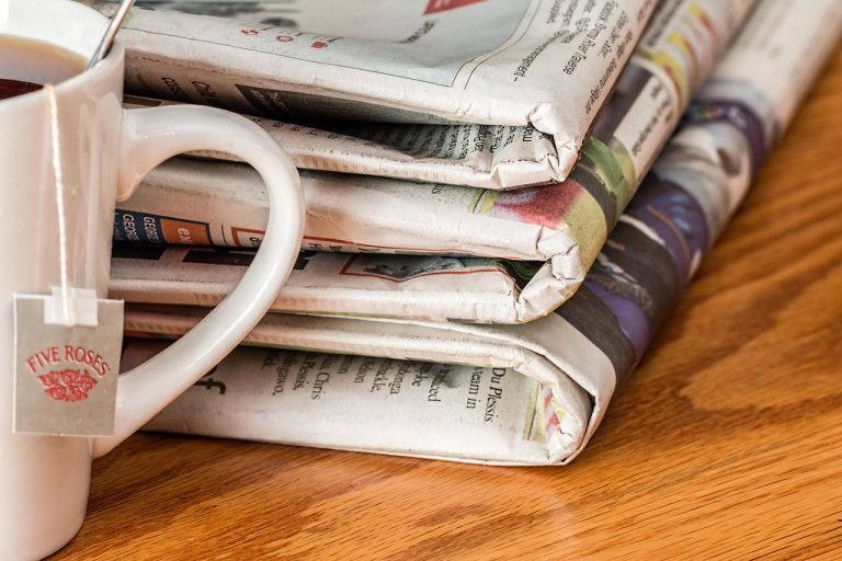 Price band advertisement: a stack of folded newspapers beside a cup of tea, where IPO ads are printed