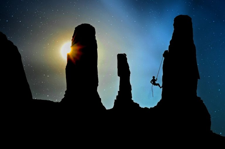 Treynor ratio: a roped climber silhouetted between tall rock towers under a starry sky