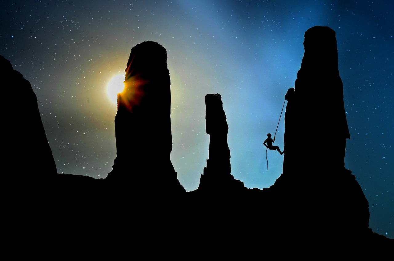 Treynor ratio: a roped climber silhouetted between tall rock towers under a starry sky