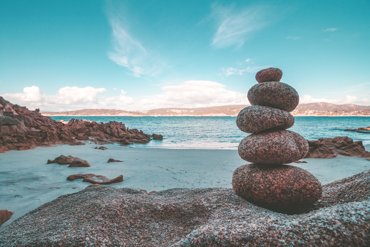 Sharpe ratio concept: a stack of balanced stones on a rocky beach with the sea behind