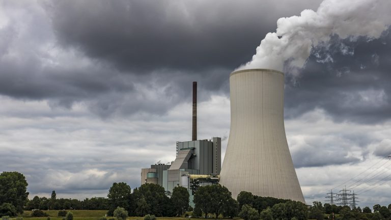 Adani Power Q2 results: cooling tower and chimney of a coal-fired power station under grey clouds