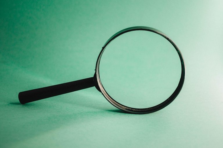 IPO grading concept: a magnifying glass on a plain green background, standing for a close look at a company before its IPO