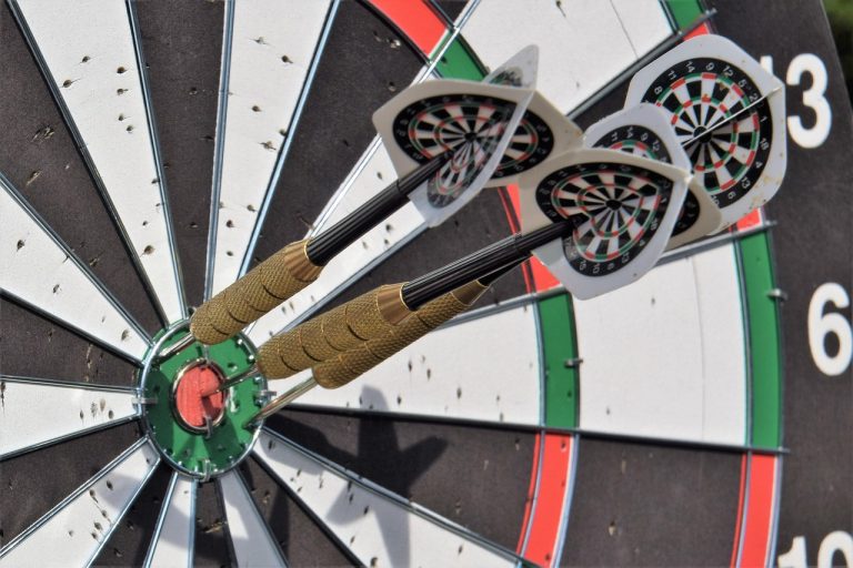 Information ratio concept: three darts grouped tightly on a dartboard, a symbol of consistent outperformance