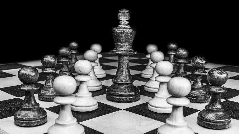 Superior voting rights shares concept: a tall chess king standing among many pawns on a black and white board