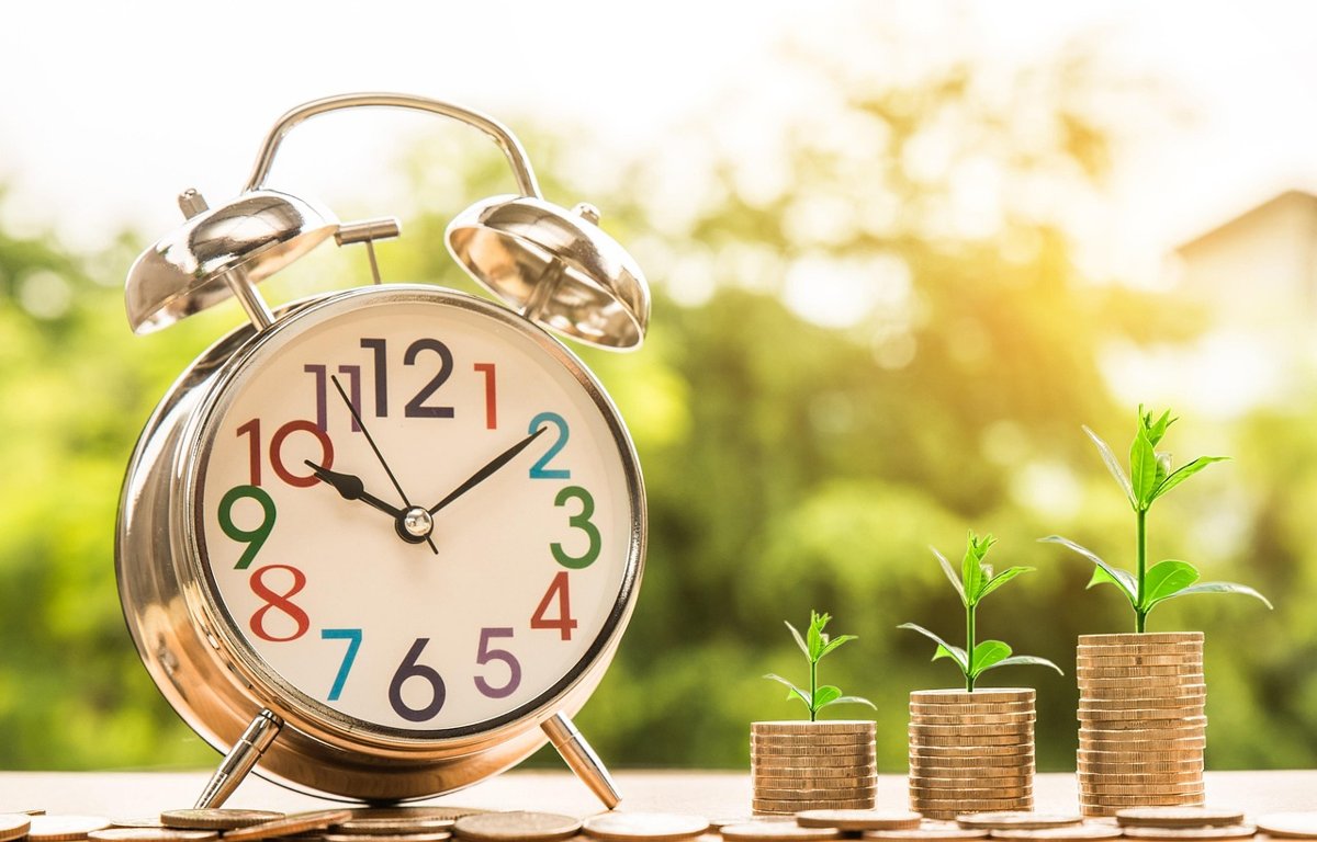 Treasury bills in India concept: an alarm clock beside three rising stacks of coins with seedlings, for short-term government bills maturing over time