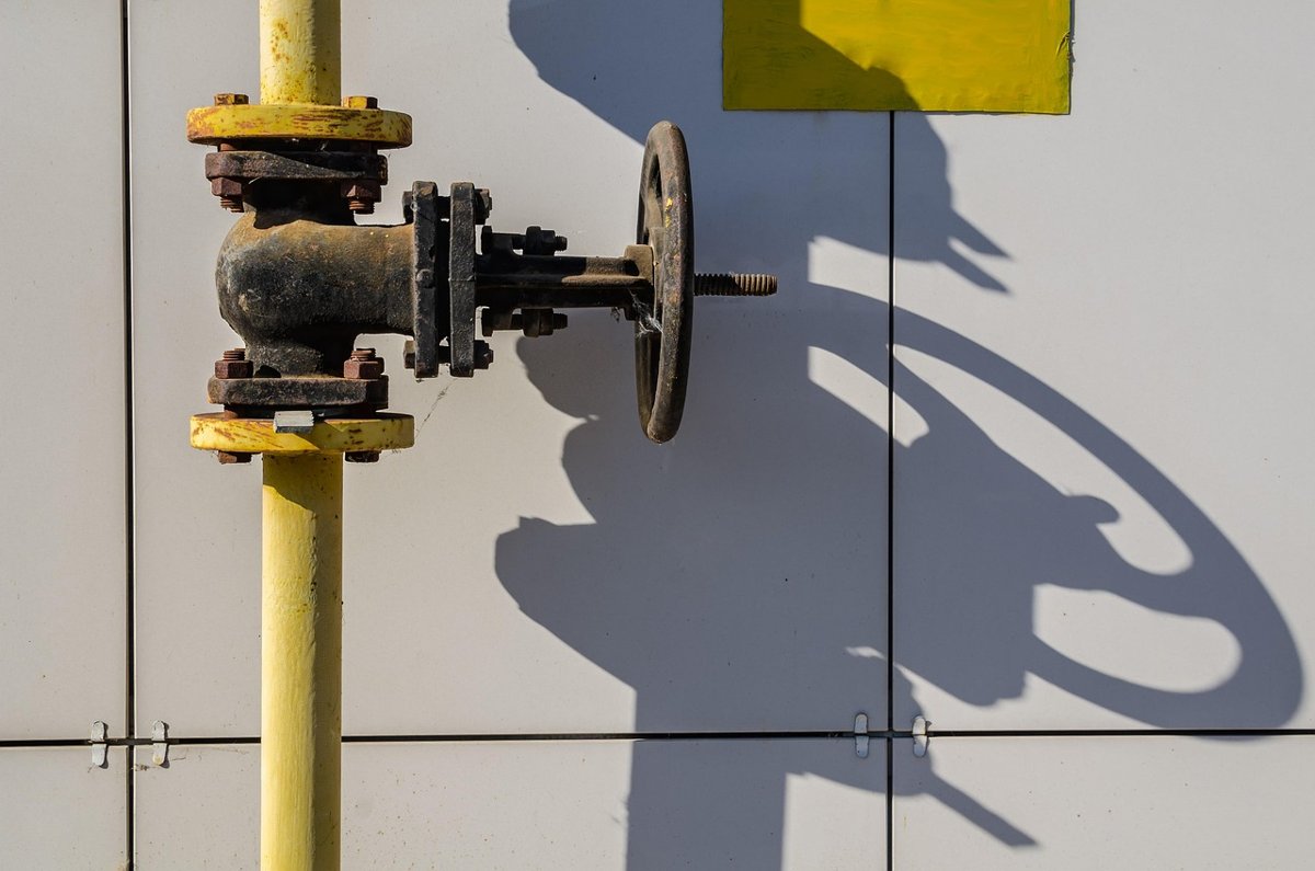 Adani Total Gas Q2 results: a yellow city gas pipeline with a valve against a white wall