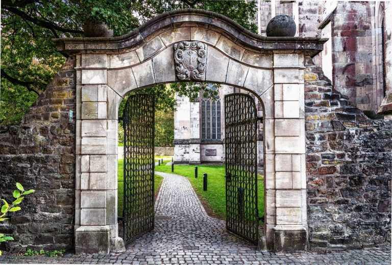 IPO eligibility norms SEBI: an open wrought-iron gate in a stone archway leading onto a cobbled path