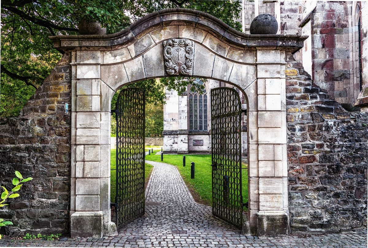 IPO eligibility norms SEBI: an open wrought-iron gate in a stone archway leading onto a cobbled path
