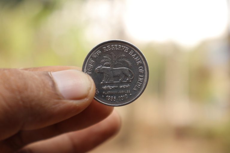 Yes Bank Moody's rating: a hand holding an Indian rupee coin issued by the Reserve Bank of India