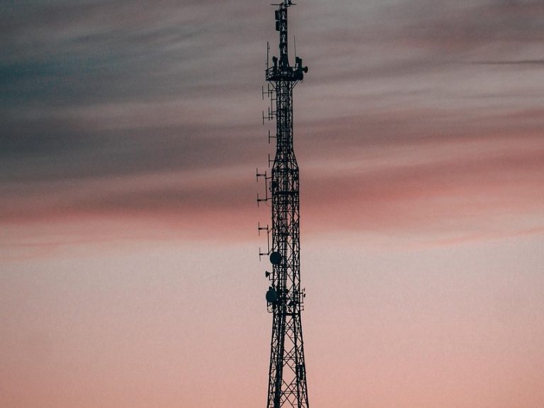 Indus Towers Q2 results: telecom tower with antennas silhouetted against a pink evening sky