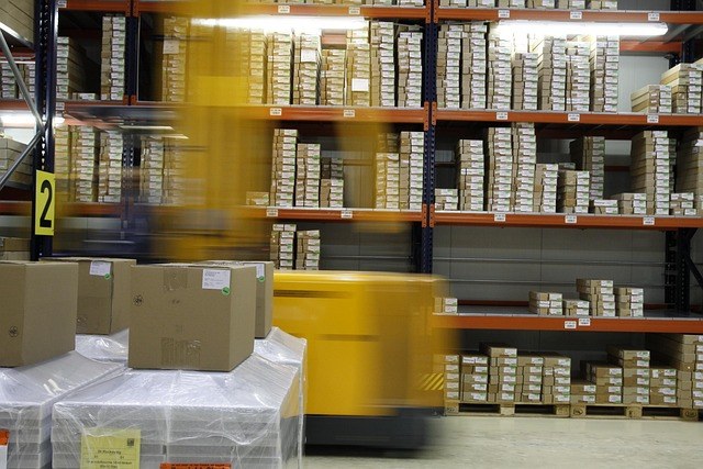 Inventory days meaning: warehouse racks stacked with boxed stock and a forklift moving past