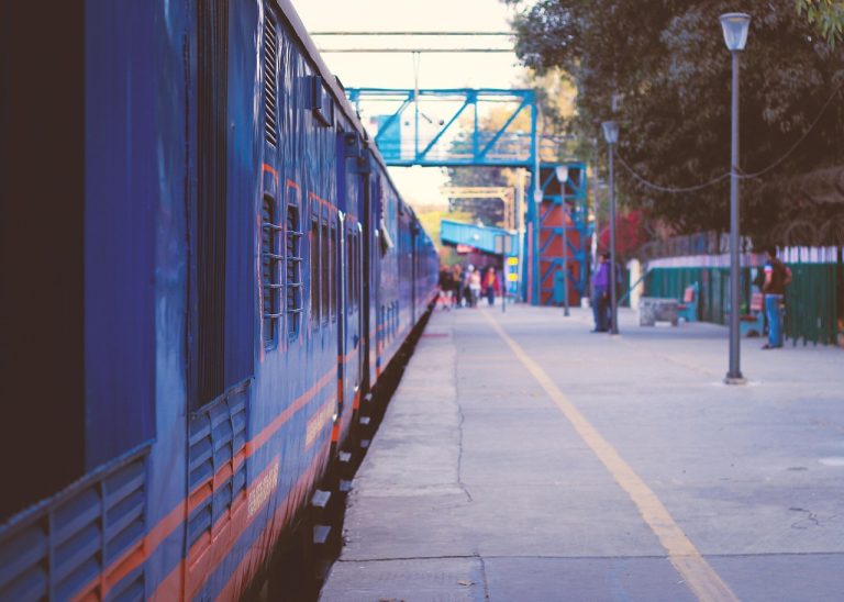 ixigo Q2 results October 17: blue passenger train beside a quiet railway station platform in Delhi