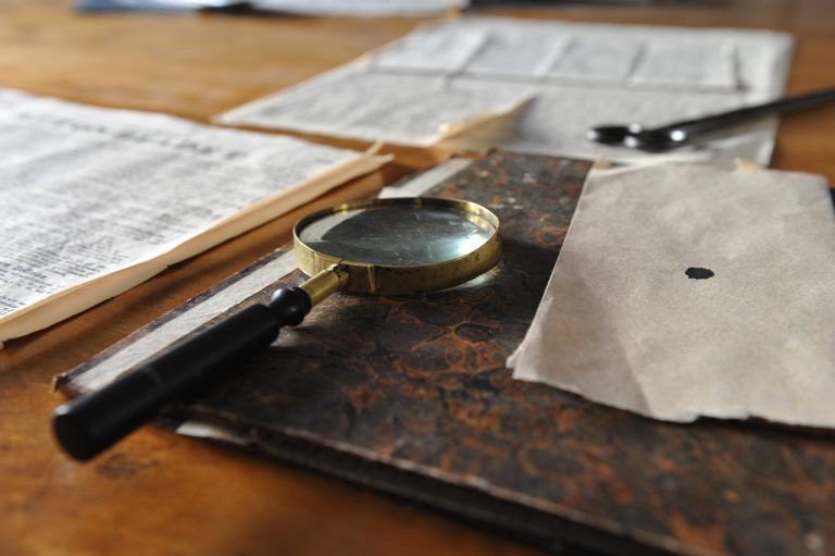Key audit matters meaning: a brass magnifying glass resting on an old ledger beside papers