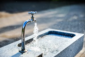 Liquid fund concept: water flowing from a steel tap into a stone basin