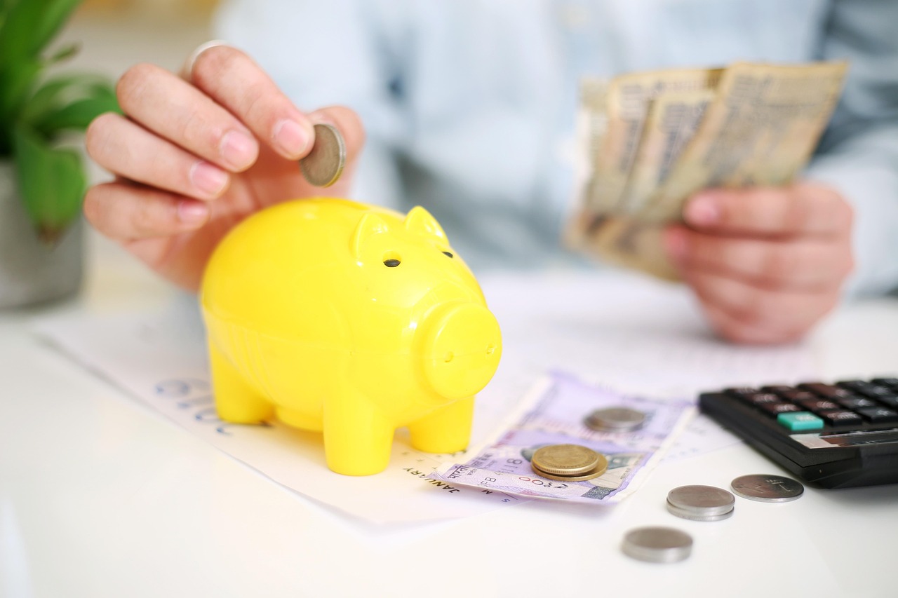 Listing gains tax India: hands counting rupee notes beside a yellow piggy bank and a calculator