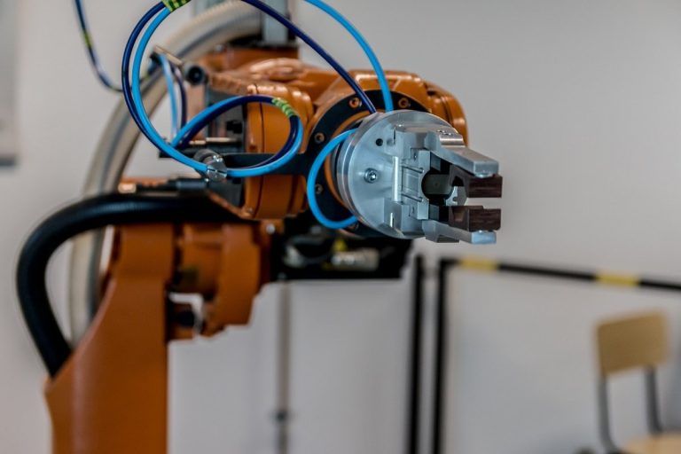LTTS Q2 results: an orange industrial robot arm with a metal gripper in an engineering lab
