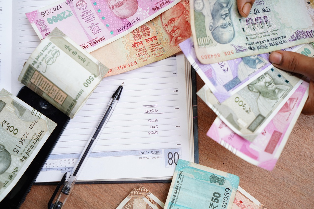 Margin trading facility: a hand counting Indian rupee notes over a ledger book on a desk
