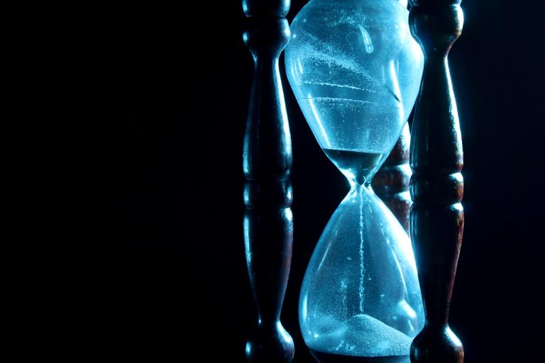Max pain theory options expiry: hourglass with sand running out against a dark background