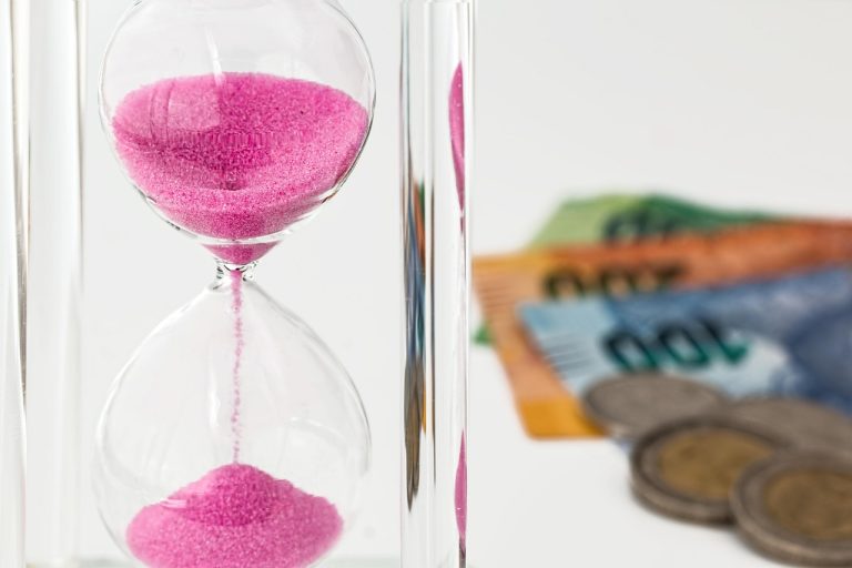 Medium duration debt fund concept: hourglass with pink sand beside banknotes and coins