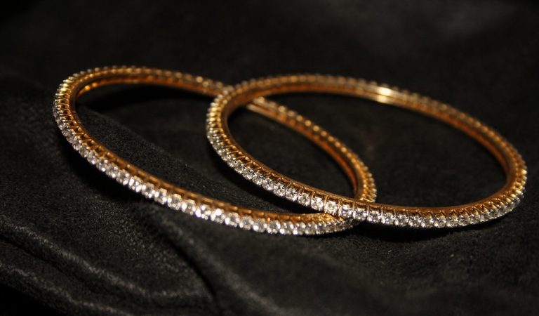 MK Sons Fine Jewels IPO: two gold bangles set with white stones on black velvet