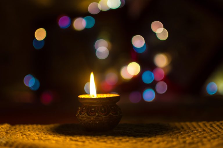 Muhurat trading 2026: a lit clay diya glowing against colourful Diwali bokeh lights