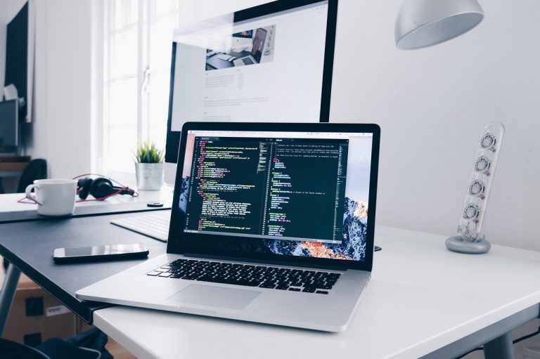 Nifty IT weekly gain: a laptop showing code on a desk in a bright software office