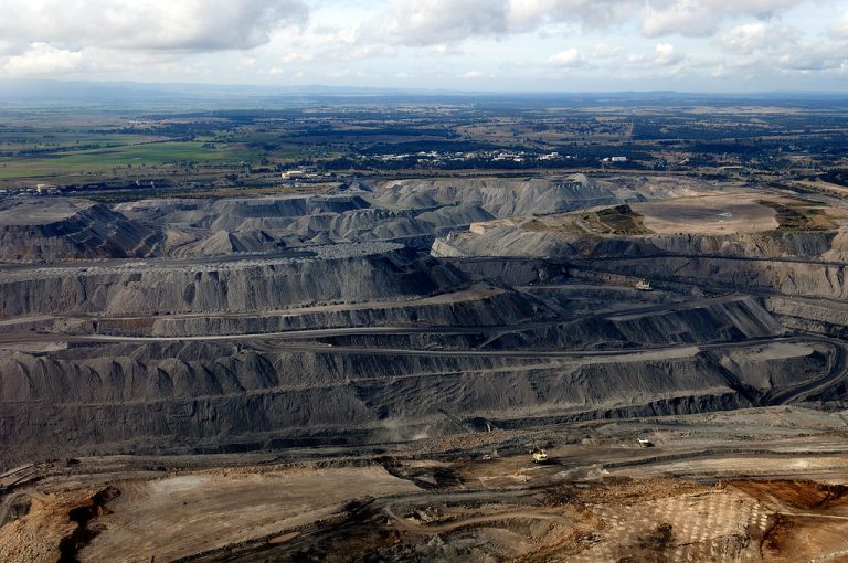 BCCL Q2 results: terraced benches of a large open-cut coal mine with haul roads and mining trucks