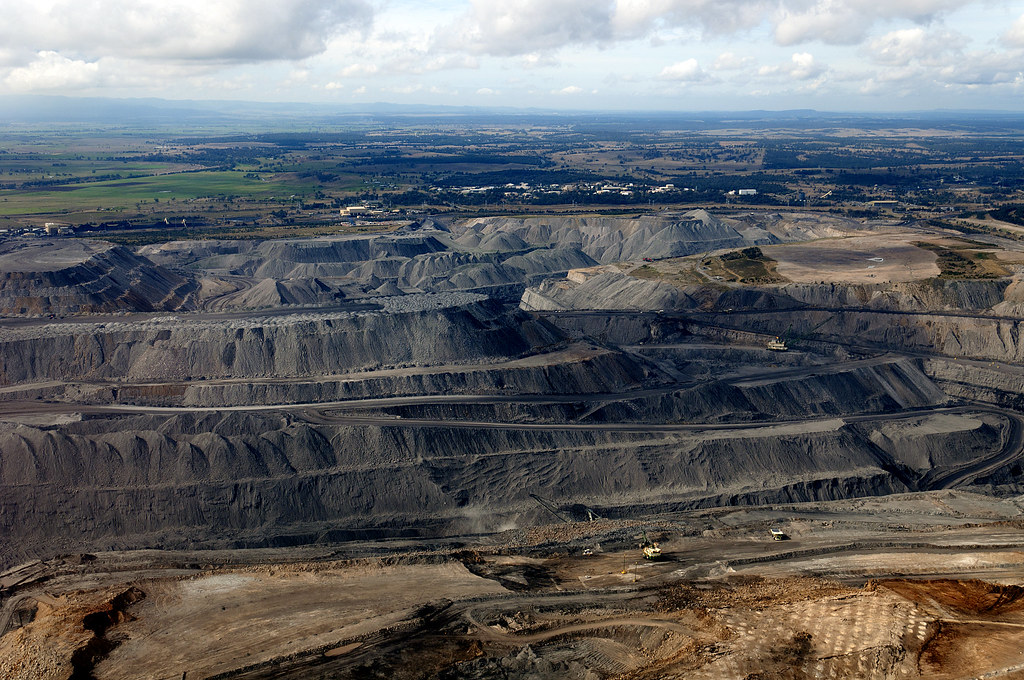 BCCL Q2 results: terraced benches of a large open-cut coal mine with haul roads and mining trucks