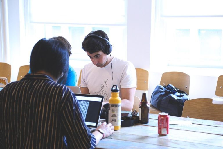 Innovators growth platform: young startup team working on laptops at a shared wooden table