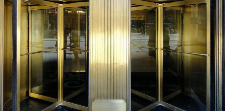 Portfolio turnover ratio concept: brass revolving doors at a busy office building entrance