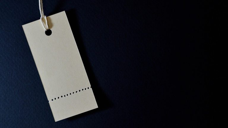 Price band in IPO: a blank paper price tag hanging on a string against a dark blue background