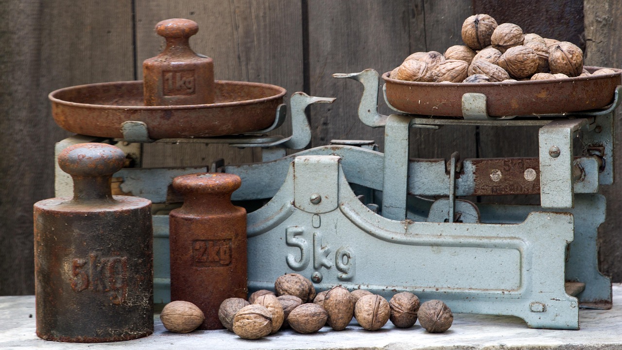 R-multiple concept: an old balance scale with iron weights on one pan and walnuts on the other