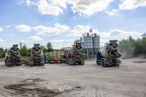 Realisation per tonne in cement results: concrete mixer trucks lined up at a cement silo plant