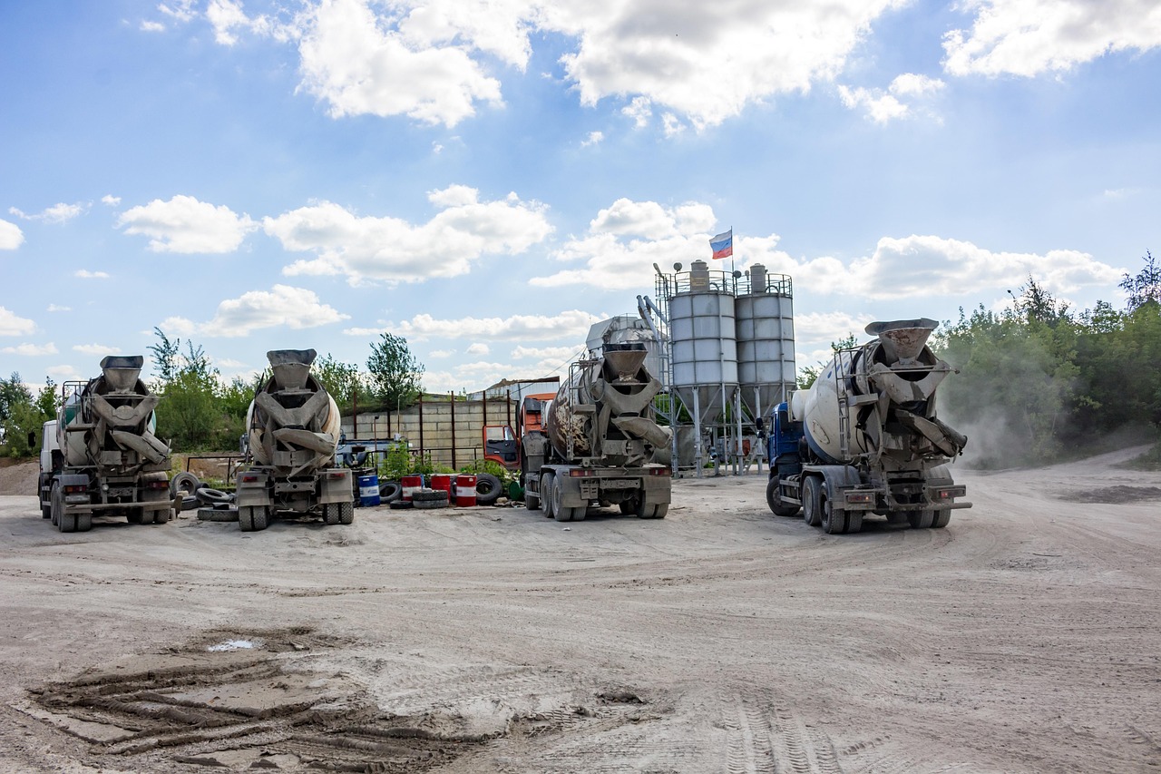 Realisation per tonne in cement results: concrete mixer trucks lined up at a cement silo plant