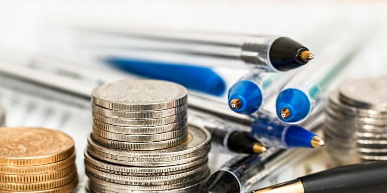 Rolling returns mutual fund concept: stacks of coins beside ballpoint pens on a desk