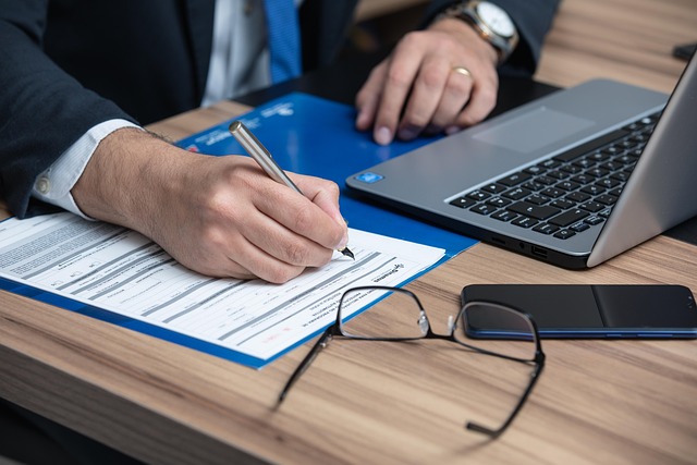 SEBI ICDR review: a person signing an offer document at a desk beside a laptop
