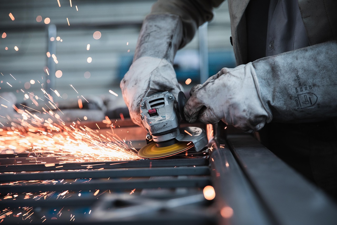SEBI SME IPO proposal: worker using an angle grinder on steel in a small manufacturing workshop