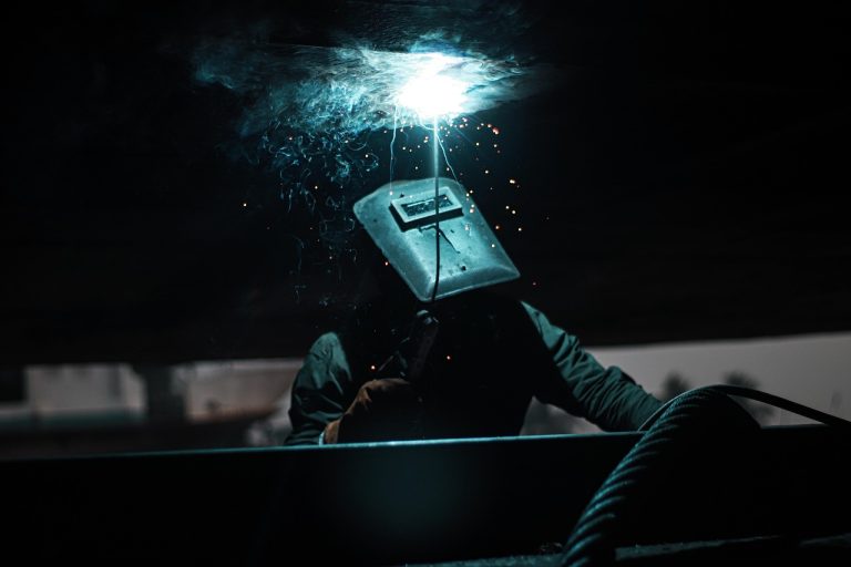 Sensex rebound: a welder in a protective mask working on steel as sparks fly
