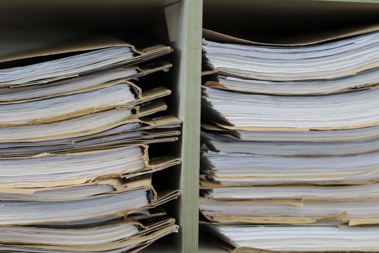 Share transfer agent role: shelves stacked with shareholder record files in an office