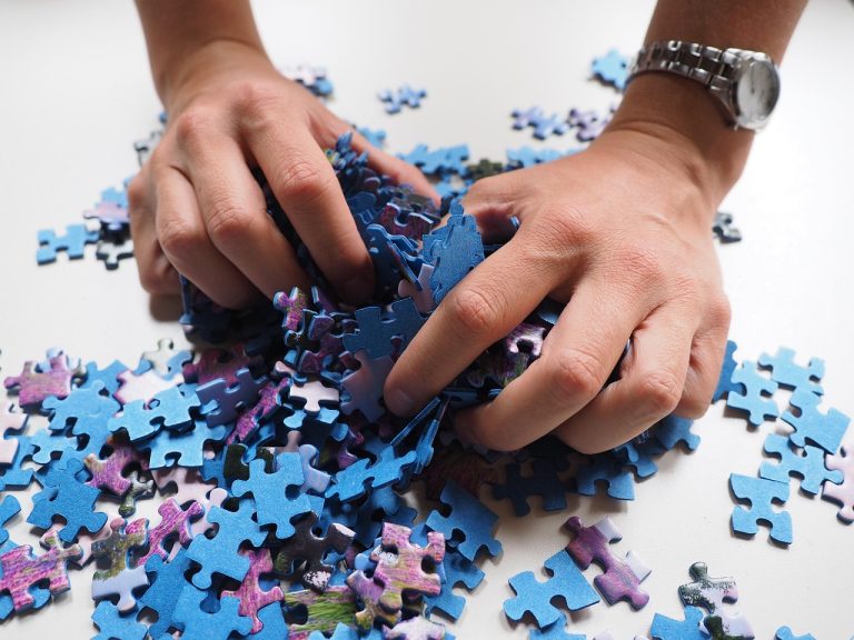 Shareholding pattern analysis concept: hands sorting a pile of blue jigsaw puzzle pieces