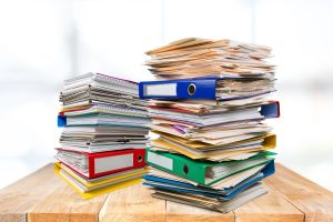 Suspense escrow demat account: stacks of share paperwork in office binders on a desk
