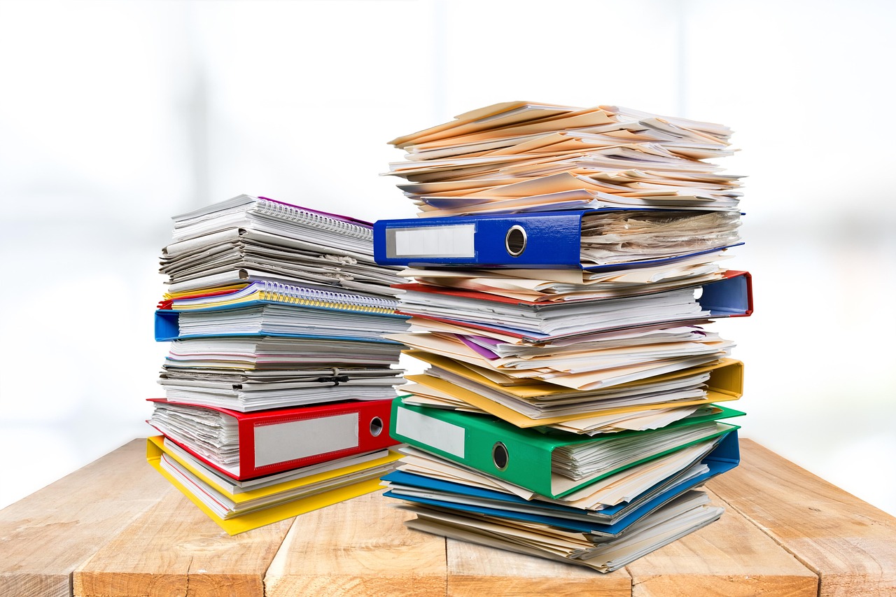 Suspense escrow demat account: stacks of share paperwork in office binders on a desk